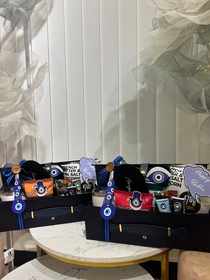 A closer look at the evil-eye themed Rakhi hampers. These black trunk boxes are filled with snacks and goodies, all sticking to the protective and trendy theme.