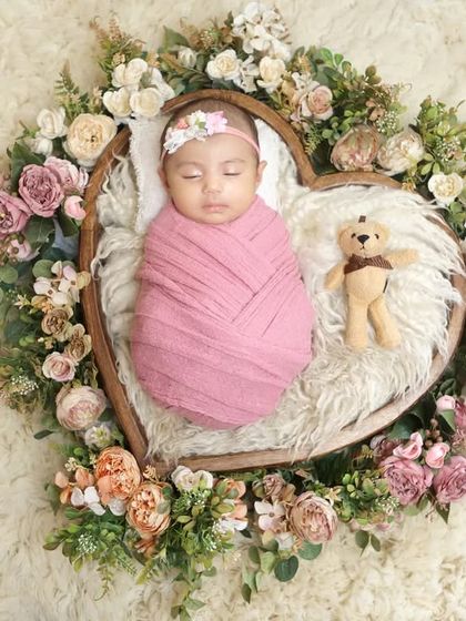 A slightly different pose within the floral heart basket, this time with a tiny teddy bear companion for an extra touch of cuteness.