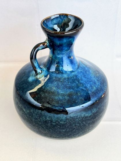 A midnight blue vase with a delicate handle. This wheel-thrown piece has a classic, elegant shape, and the deep blue glaze is simply mesmerizing.