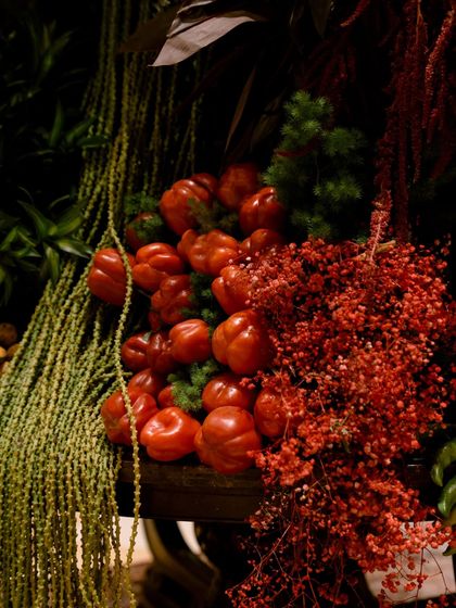 A close-up on the surprising textures within the arrangement. Here, bright red bell peppers are nestled amongst cascading green foliage and delicate red florals. I believe in adding unexpected elements that delight the senses and make you look twice.
