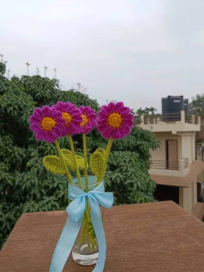 A vase of three magenta daisy stems.