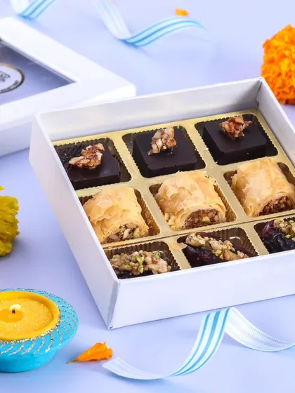 This elegant white gift box contains a curated selection of our premium festive sweets, including Baklava rolls and assorted nut-filled dates, complete with a silver coin.