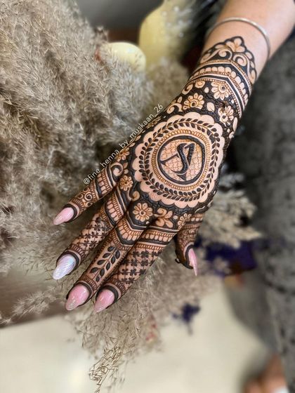 A close-up of a personalized mandala design with the initials 'SJ'. The fine lines and shading create a beautiful 3D effect.