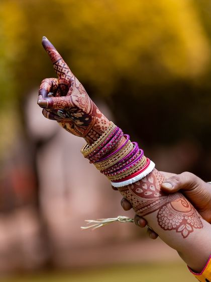 An artistic shot of a bride's hand, with the focus on the detailed mehendi and colorful bangles.