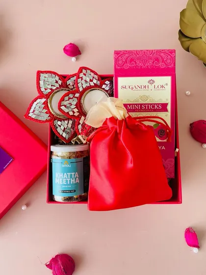 An overhead shot of the red Diwali box, showing the neat arrangement of the T-light holder, snack jar, potli, and incense box.