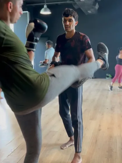 A coach holding pads for a participant, providing one on one guidance during the workshop.
