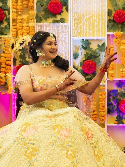 A joyful candid of the bride at her Haldi. She's wearing beautiful floral jewelry, and her makeup is fresh and minimal to complement the natural theme.