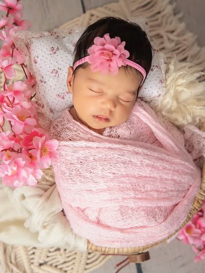 An overhead view of a baby girl wrapped cozily and surrounded by beautiful cherry blossoms. This angle is perfect for capturing their sweet, tiny features.