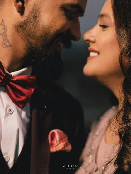 A close-up of the couple, their faces close, sharing a smile. The groom's red bow tie adds a pop of color to this intimate and romantic portrait from their engagement shoot.