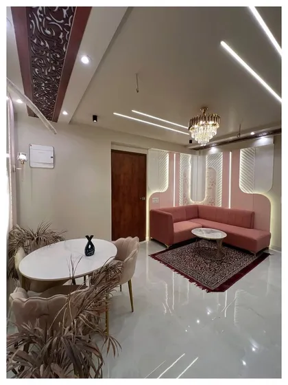 This living and dining space uses a soft pink and white color scheme. It features a custom L-shaped pink sofa, a modern dining set, and unique curved wall panels with integrated lighting.