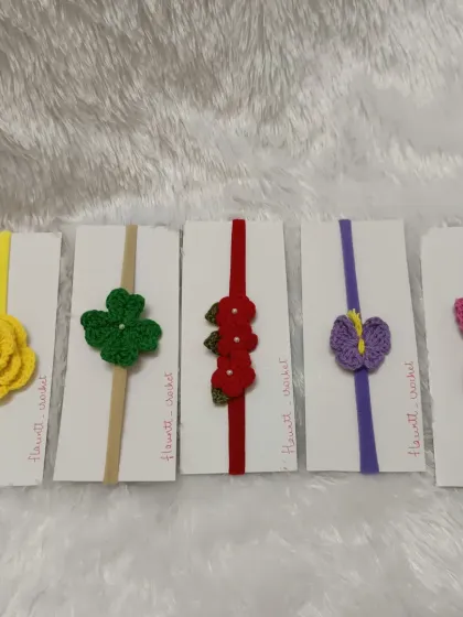 I offer a wide range of custom handmade headbands. This collection shows a variety of designs on soft nylon bands, including a yellow rose, a lucky clover, and a purple butterfly, each made to be gentle on a baby's head.