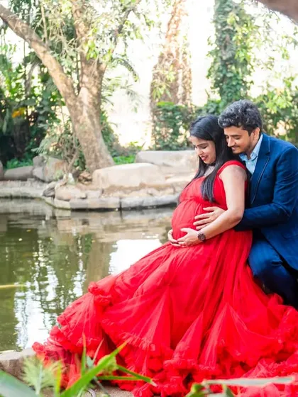 A serene and romantic portrait of a couple by the water. The rich red of her ruffled gown is a stunning contrast to the calm, natural surroundings.