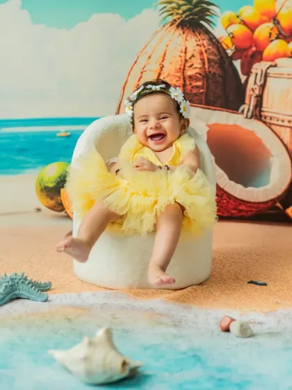 Nothing beats a genuine, happy laugh. This 'Beach Baby' setup is a favorite for sitter sessions, using a vibrant backdrop, soft sand, and themed props to create a fun, summery vibe in my Thane studio any time of year.