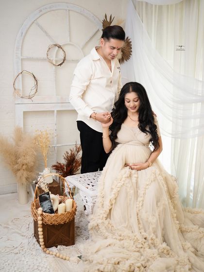 A sweet portrait of the expecting couple in a light-filled boho studio. The husband's gentle hold and their happy expressions radiate warmth and love.