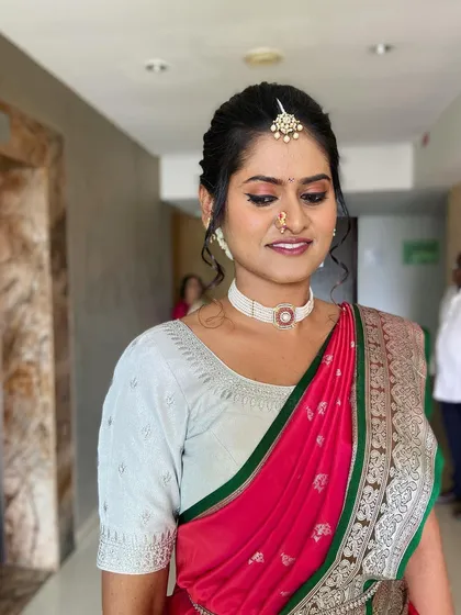 A beautiful Maharashtrian bride, looking serene and elegant. Her makeup is classic and her hair is styled in a neat updo with a maang tikka.