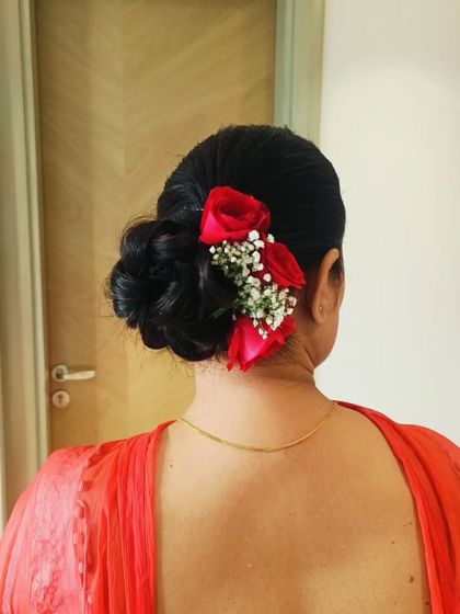 A low, intricate bun adorned with fresh red roses and baby's breath. This style is perfect for a bride who wants a classic floral look that is both elegant and secure.