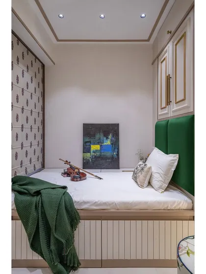 A cozy guest room designed to maximize a small space. The platform bed with a deep green headboard is complemented by smart overhead storage.