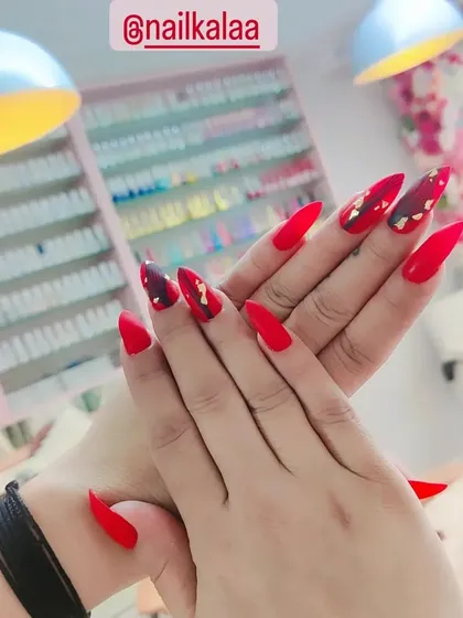 A bold and fiery set of stiletto nails in a matte red, with abstract black and gold foil accents.