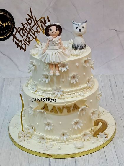 A full view of the sophisticated all-white princess theme cake. The two-tier pineapple cake is decorated with handcrafted white flowers and a personalized name banner for Aavya's 2nd birthday.
