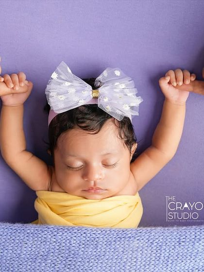 So tiny, yet holding on so tight. This sweet newborn, with a big bow and her hands grasping her parents' fingers, shows the strength in even the smallest of beings.