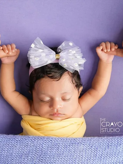 So tiny, yet holding on so tight. This sweet newborn, with a big bow and her hands grasping her parents' fingers, shows the strength in even the smallest of beings.