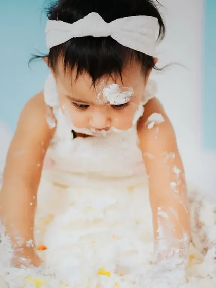 A close up of the happy mess. Capturing these sensory details, like fingers covered in frosting, is what makes a cake smash session so special and memorable.