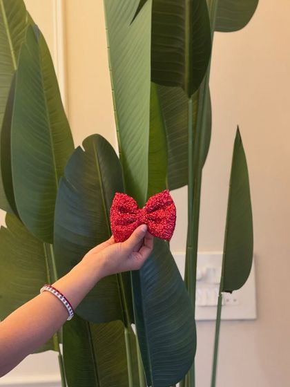 A close-up of the sparkly red bow clip. It's attached to a simple clip, making it easy to wear.