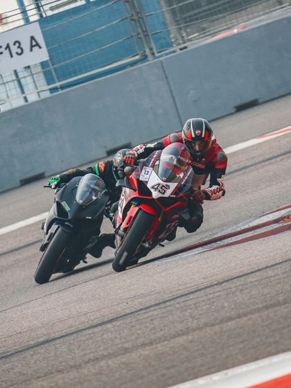 Two riders in a tight battle, leaning hard into a turn at the Buddh International Circuit. This image captures the essence of competitive track riding and pushing for every advantage.
