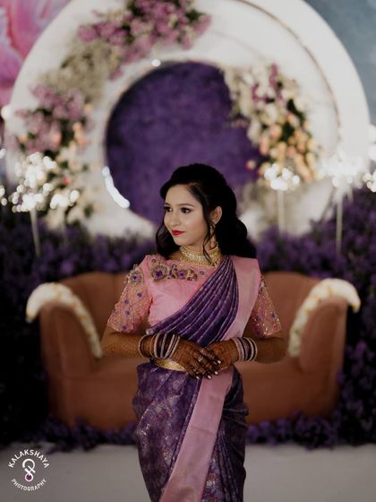 A beautiful portrait of the bride at her reception, with a stunning purple floral arrangement in the background.
