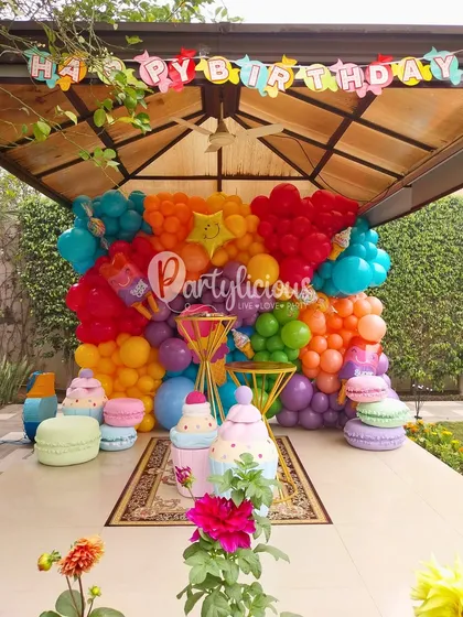 Welcome to candyland! This vibrant, rainbow-colored balloon wall was the perfect backdrop for a sweet-themed birthday. We added giant macaron and cupcake props to complete the delicious look.