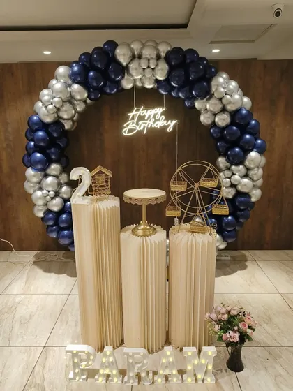 A sophisticated blue, silver, and white theme for Param's 2nd birthday. The full balloon ring, neon sign, and decorative props like a miniature Ferris wheel create a polished and celebratory look.