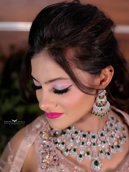 A close-up of the makeup, featuring bold pink lipstick and shimmery eyeshadow, paired with a diamond and emerald necklace.