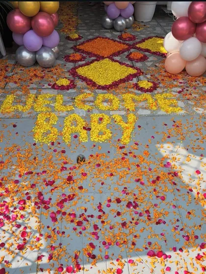 A close-up of the floor decoration, with 'WELCOME BABY' written using yellow flower petals.