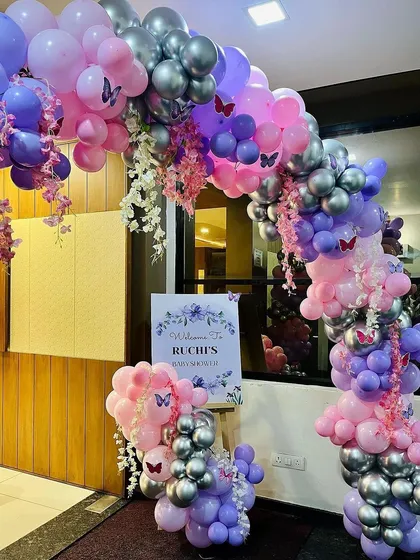 A gorgeous butterfly-themed balloon arch at an entrance, decorated in shades of purple, pink, and silver, with delicate butterfly accents. This was for a baby shower but is perfect for birthdays too.