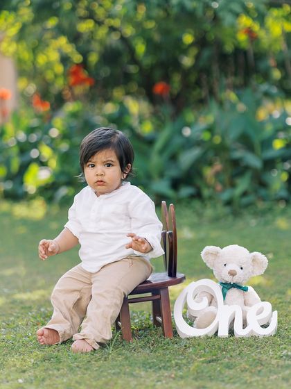 A serious moment from the birthday boy, sitting with his "ONE" sign and teddy bear. These quiet expressions are so full of personality.