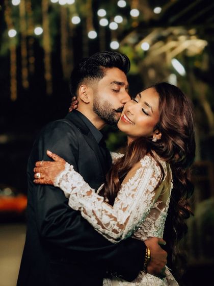 A sweet kiss on the cheek under the warm glow of evening lights. This candid night portrait captures the romance of the wedding reception.