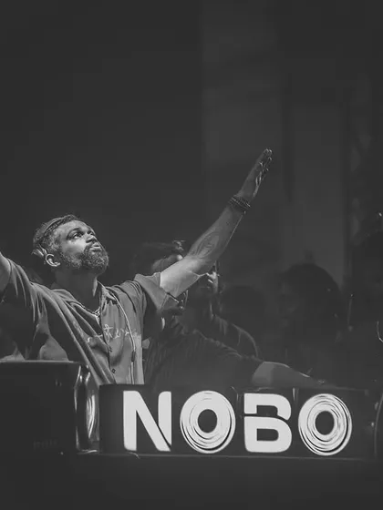 A black and white photo of me with arms raised in front of the NOBO logo, a moment of pure elation.