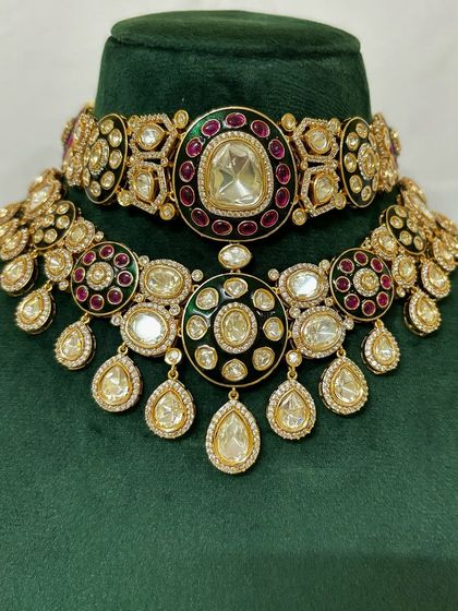 A two-piece necklace set with a choker and a matching necklace, both featuring red and green Meenakari work. This is a classic bridal rental choice.