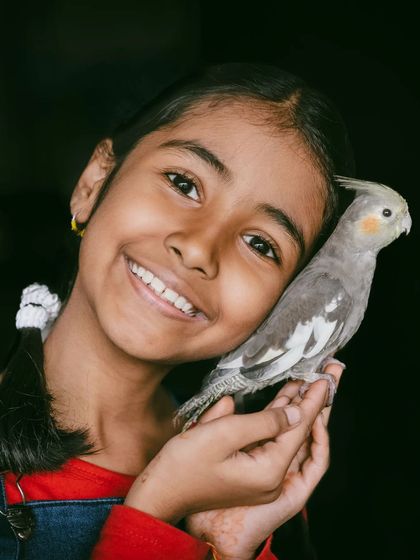 The purest love is often between a child and their pet. Capturing this gentle, smiling moment between a young girl and her cockatiel is a perfect example of the heartwarming memories I aim to preserve.