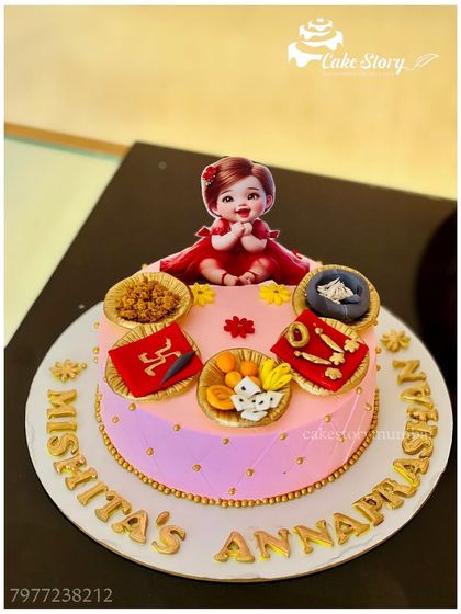A cake for a baby's Annaprasan, or first rice-eating ceremony. This pink cake is decorated with edible bowls of traditional foods and other auspicious items.