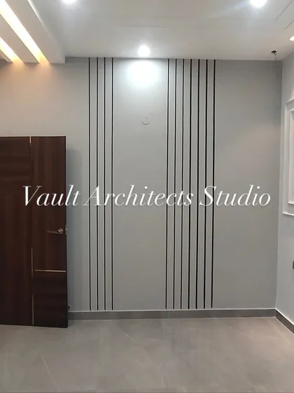 A glimpse of a finished bedroom or living space, showcasing simple elegance. The wall features a combination of vertical grooves and classic molding, adding texture and character to the room.