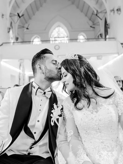 A sweet moment in the church pew, with the groom kissing the bride's forehead. This black and white candid captures the quiet moments of the day.