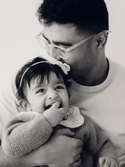 A father gently kisses his daughter's head in this tender black and white portrait. A beautiful capture of paternal love.