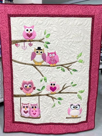 A sweet baby quilt featuring an adorable family of appliqué owls sitting on tree branches.