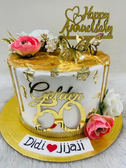 A golden 50th anniversary cake for a special "Didi & Jijaji." This white and gold masterpiece is decorated with flowers, butterflies, and a "Golden 50" topper.