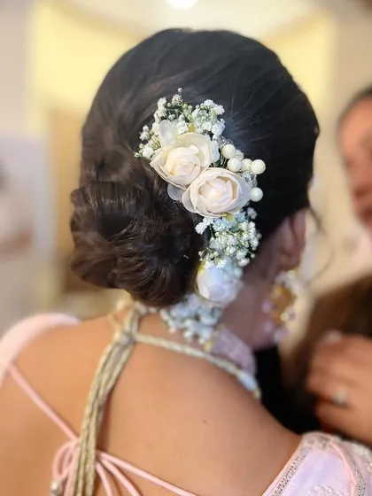 A close-up of the floral cascade, showing the delicate arrangement of flowers on the side of the bun.