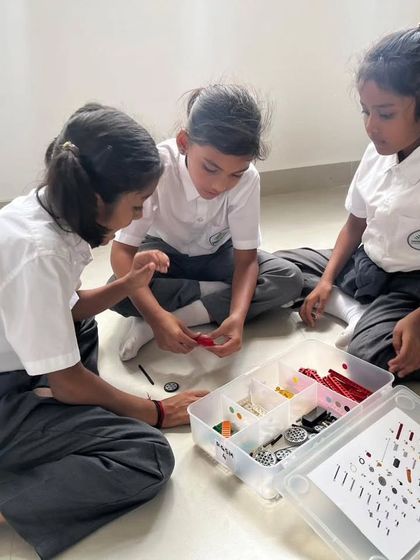 Three girls from Sadhu Vaswani International School work together, demonstrating focus and teamwork.