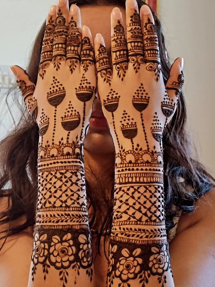 A fun and creative jhumka design. The pattern on the palms looks like chandeliers, while the arms have a classic net pattern.