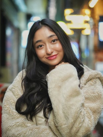A classic portrait with a beautiful smile. The composition uses the leading lines of the street and the bokeh lights to draw all the attention to her.