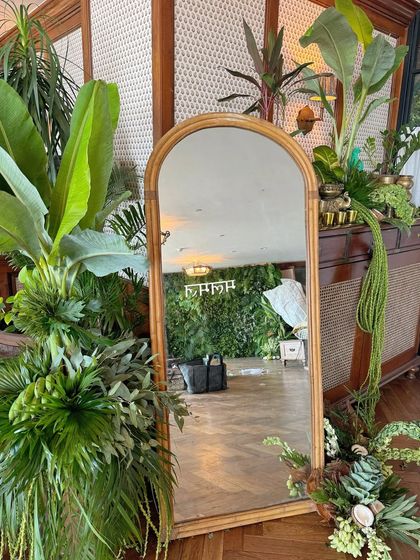 A rustic arched mirror surrounded by large tropical plants, serving as a beautiful photo spot for guests at the Shop Mul Mul event.